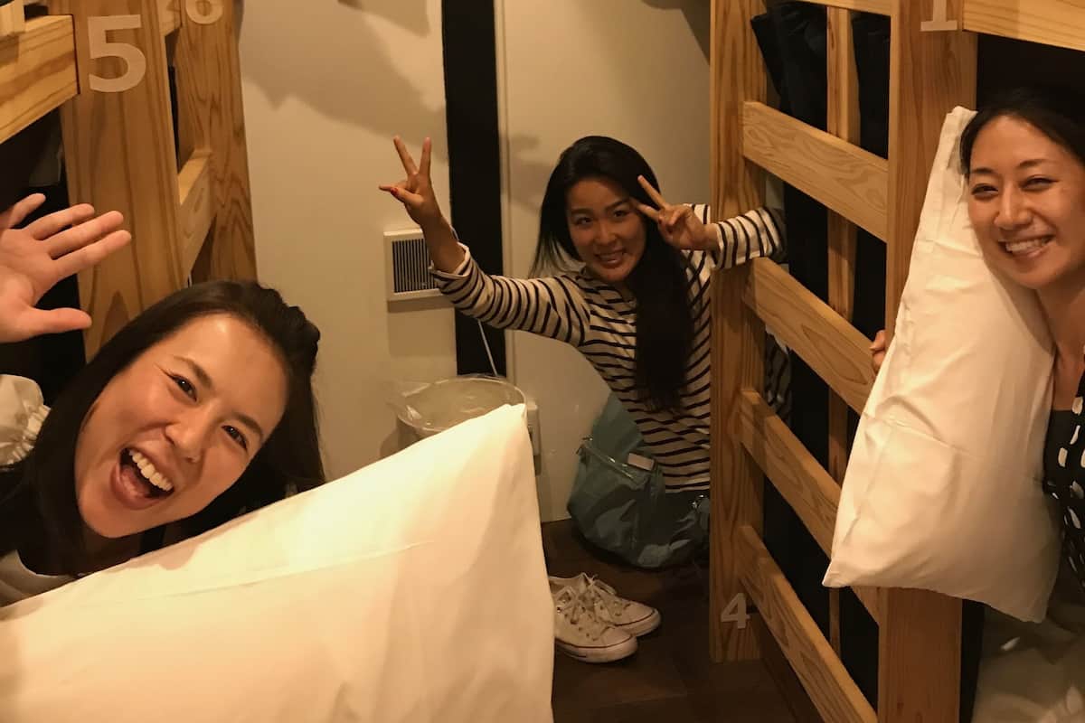 A dormitory room with bunk beds, numbered from 1 to 6, and a window with curtains.