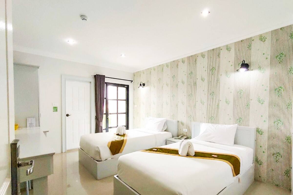 Quarto de hotel com duas camas, uma escrivaninha e um banheiro.