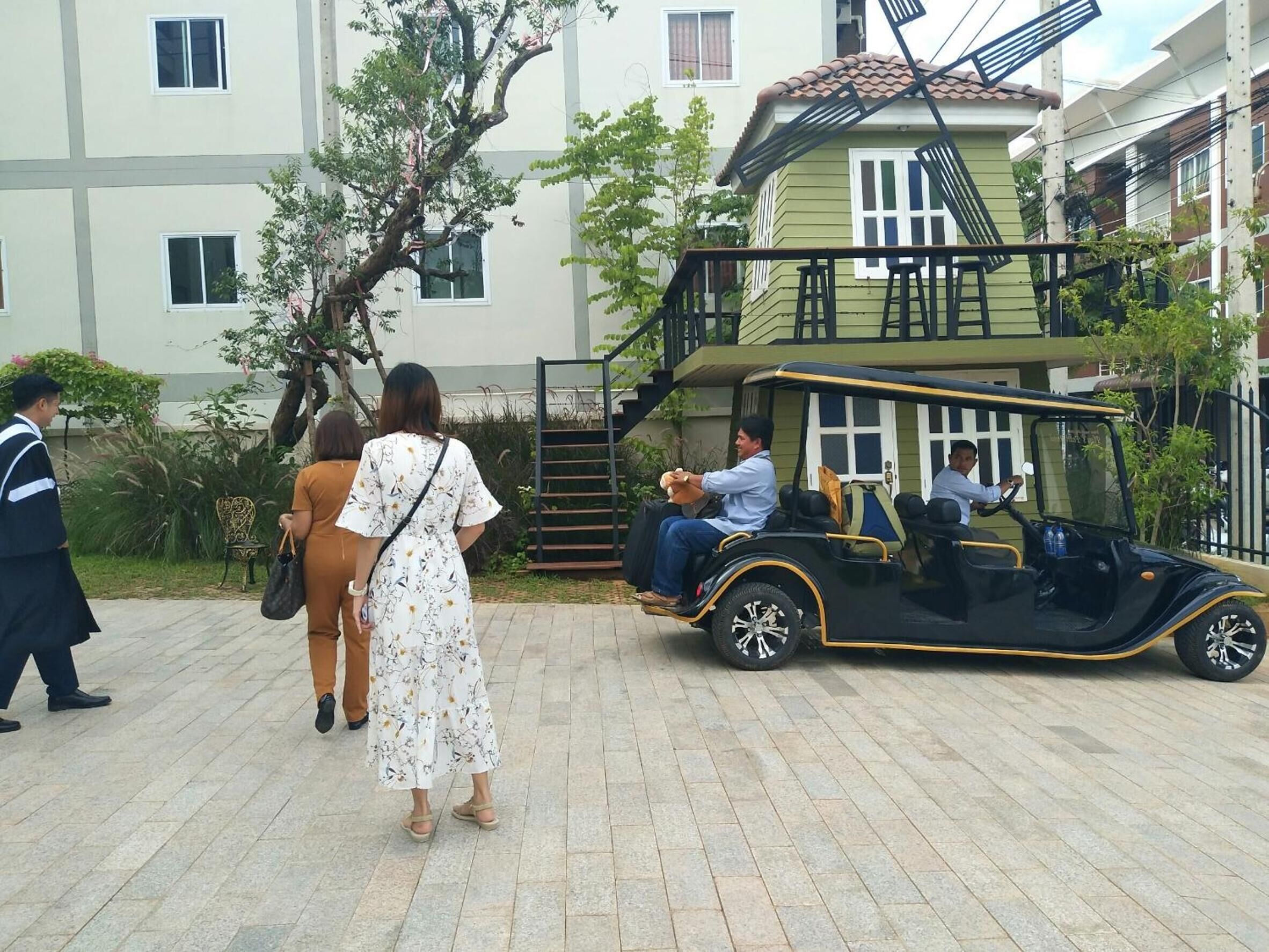 A building with a staircase leading to a balcony, surrounded by greenery.