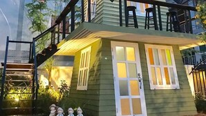 Ein zweistöckiges Haus mit Balkon, Treppe und einem kleinen Gartenbereich mit Zierfiguren.