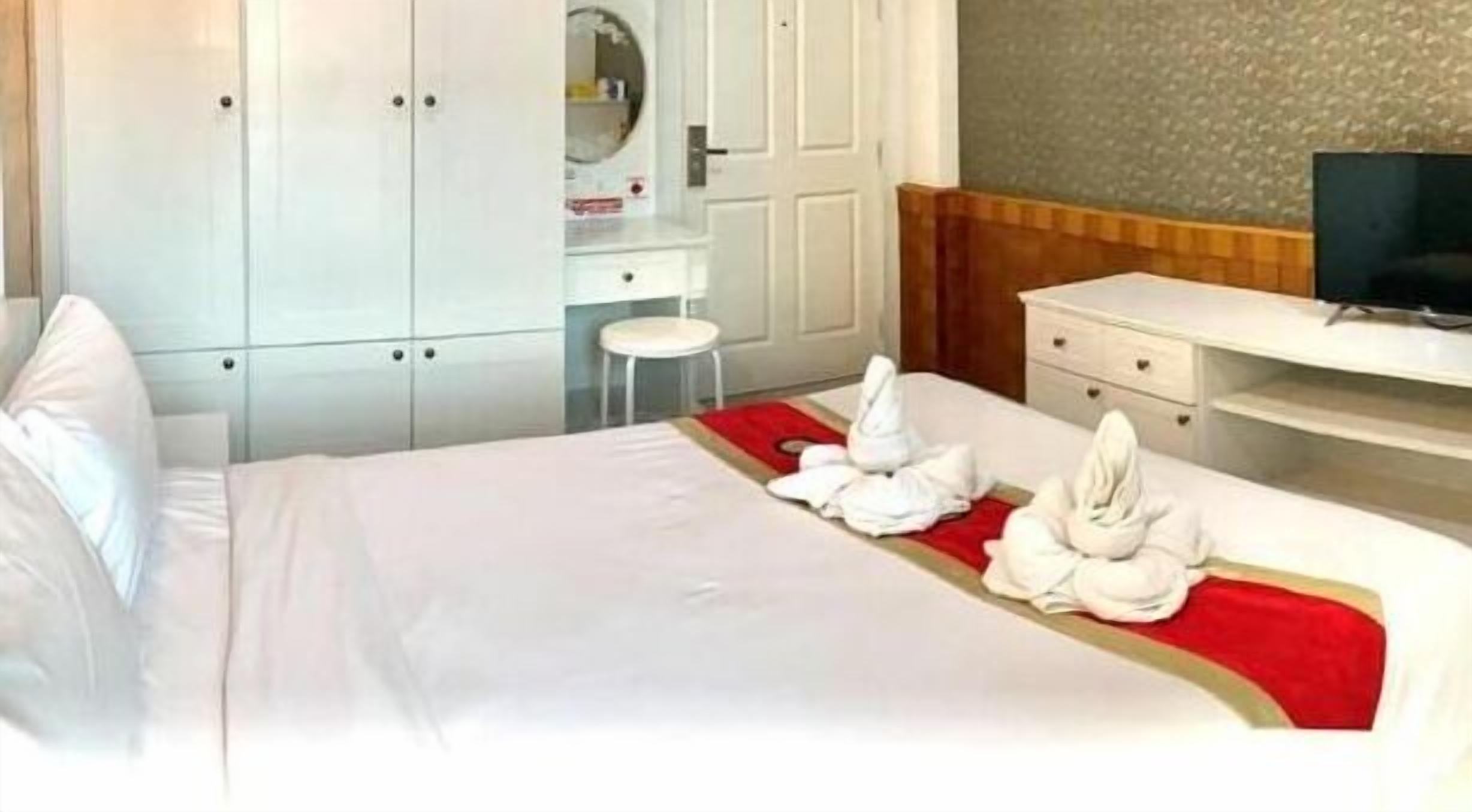 Una habitación de hotel con una cama bien hecha, televisión, escritorio y armario.