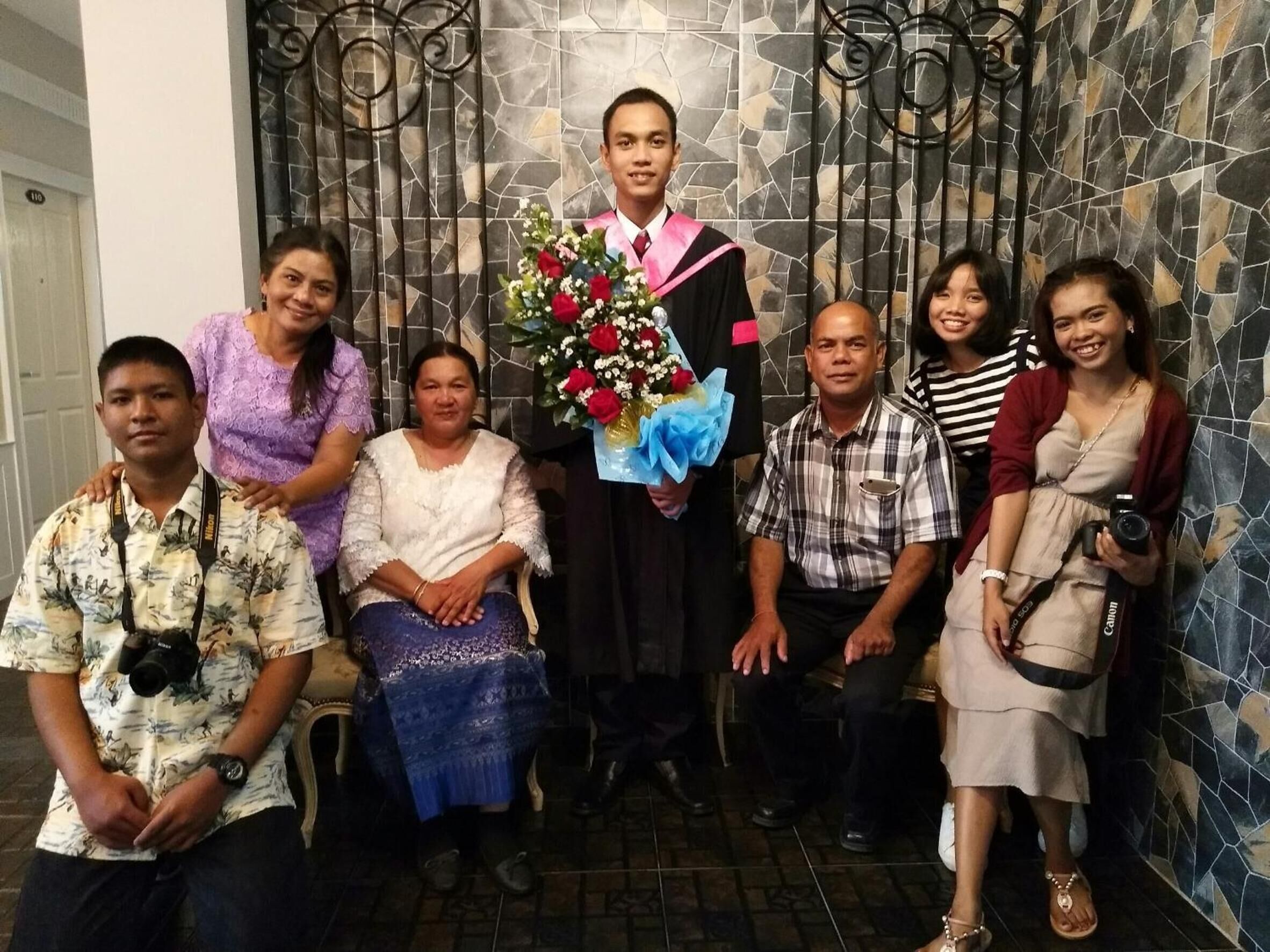 Un grup de persones fent una foto en una habitació amb una paret de rajoles i una porta amb la inscripció "110".