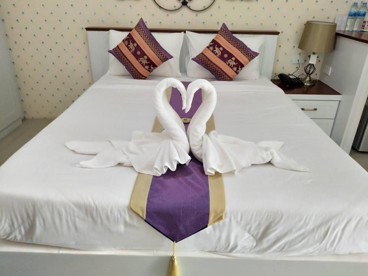 Een hotelkamer met een netjes opgemaakt bed, inclusief een handdoek creatie in de vorm van een zwaan.