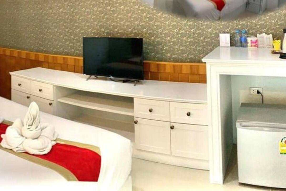 Quarto de hotel com cama, escrivaninha, televisão e mini-geladeira.