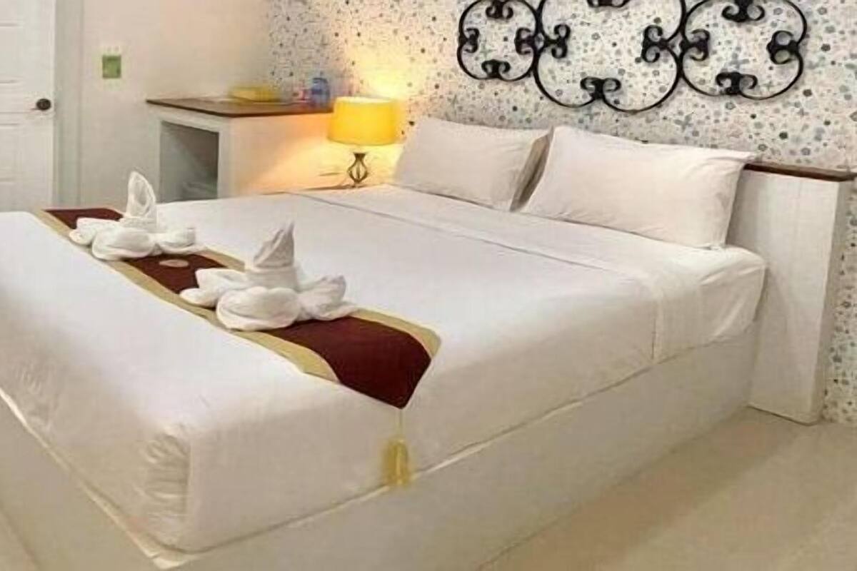 Quarto de hotel com cama, escrivaninha, cadeira, televisão e porta para uma varanda.