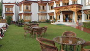 A hotel with traditional architecture, outdoor seating, and a well-maintained garden.