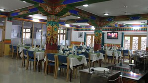 A dining area with tables set for multiple people, chairs, and a buffet counter.