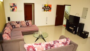 A modern living room with a sectional sofa, a glass coffee table, and a flat-screen TV.