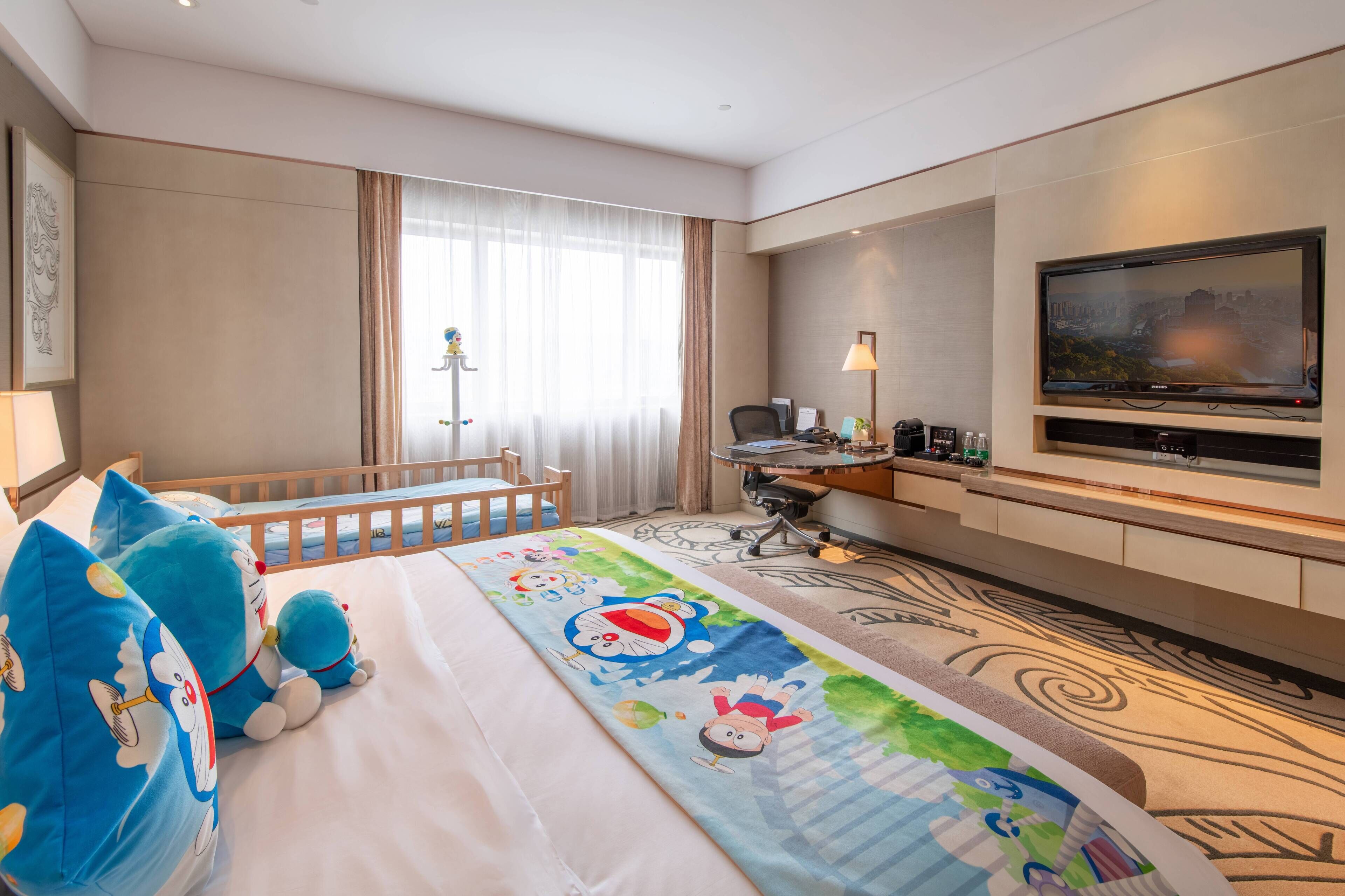 A hotel room with a bed, a desk, a chair, a TV, and a window with curtains.