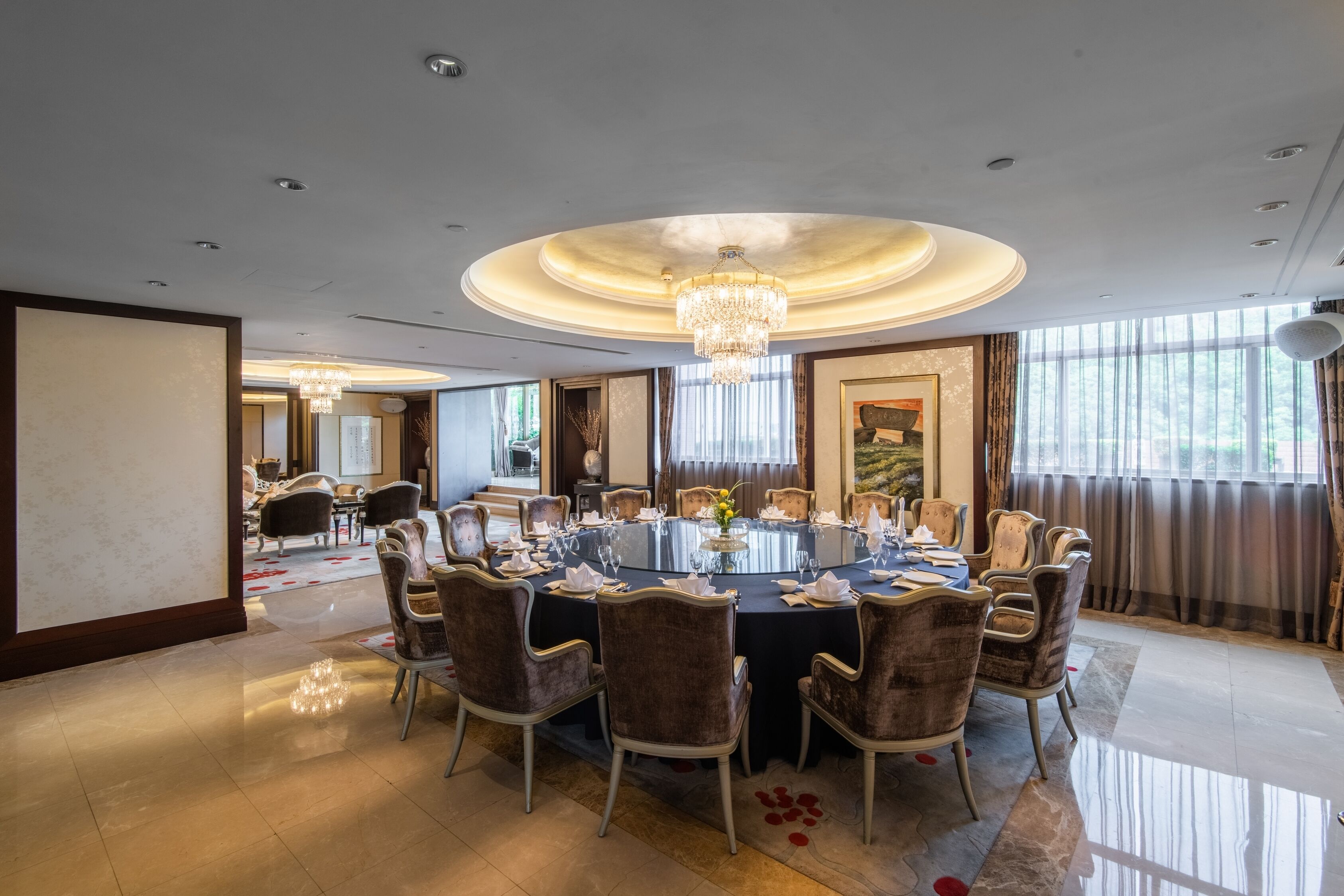 A formal dining room with a round table, chairs, and a chandelier.