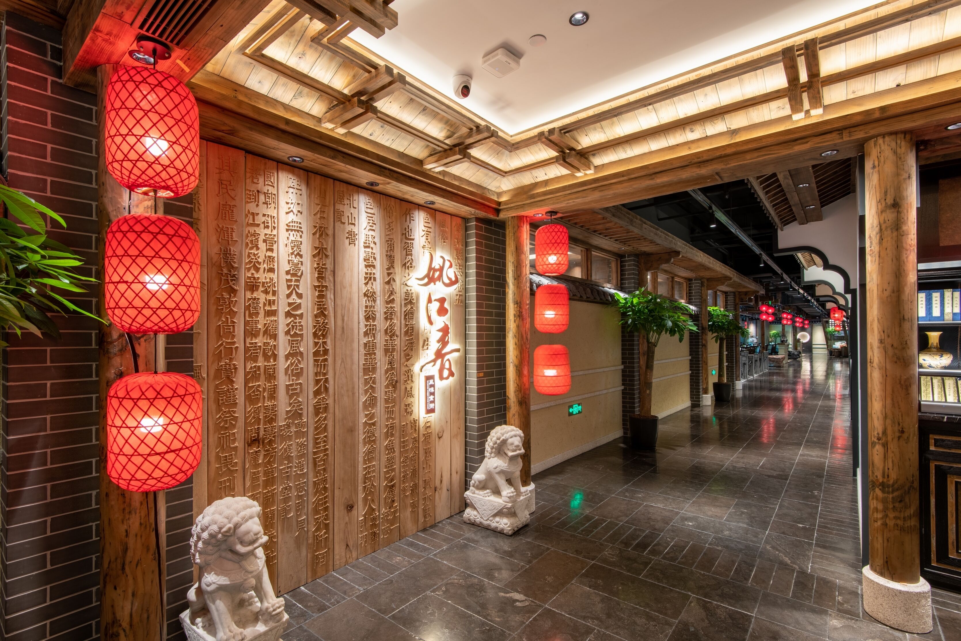 A corridor with wooden paneling, red lanterns, and a lion statue.