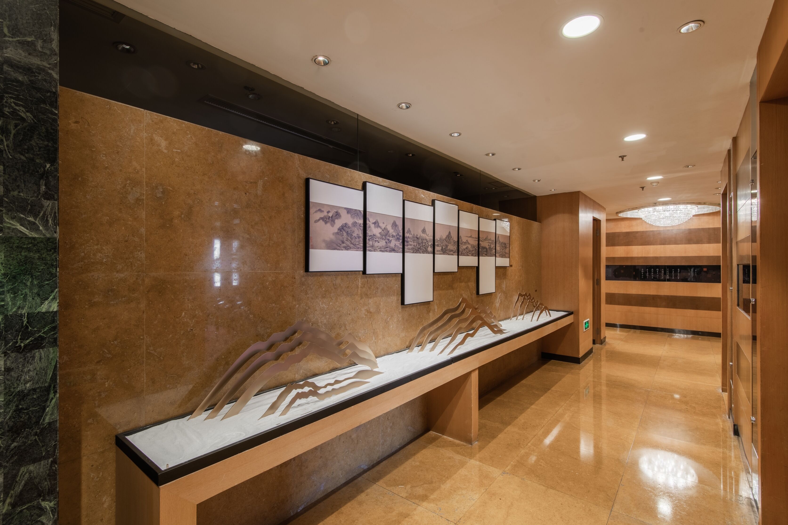 Un área de recepción con una pared de mármol, un mostrador de recepción alargado y obras de arte enmarcadas.
