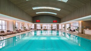 An indoor swimming pool with a high ceiling, large windows, and lounge chairs along the sides. - Grand Pacific Hotel Ningbo (Ningbo)