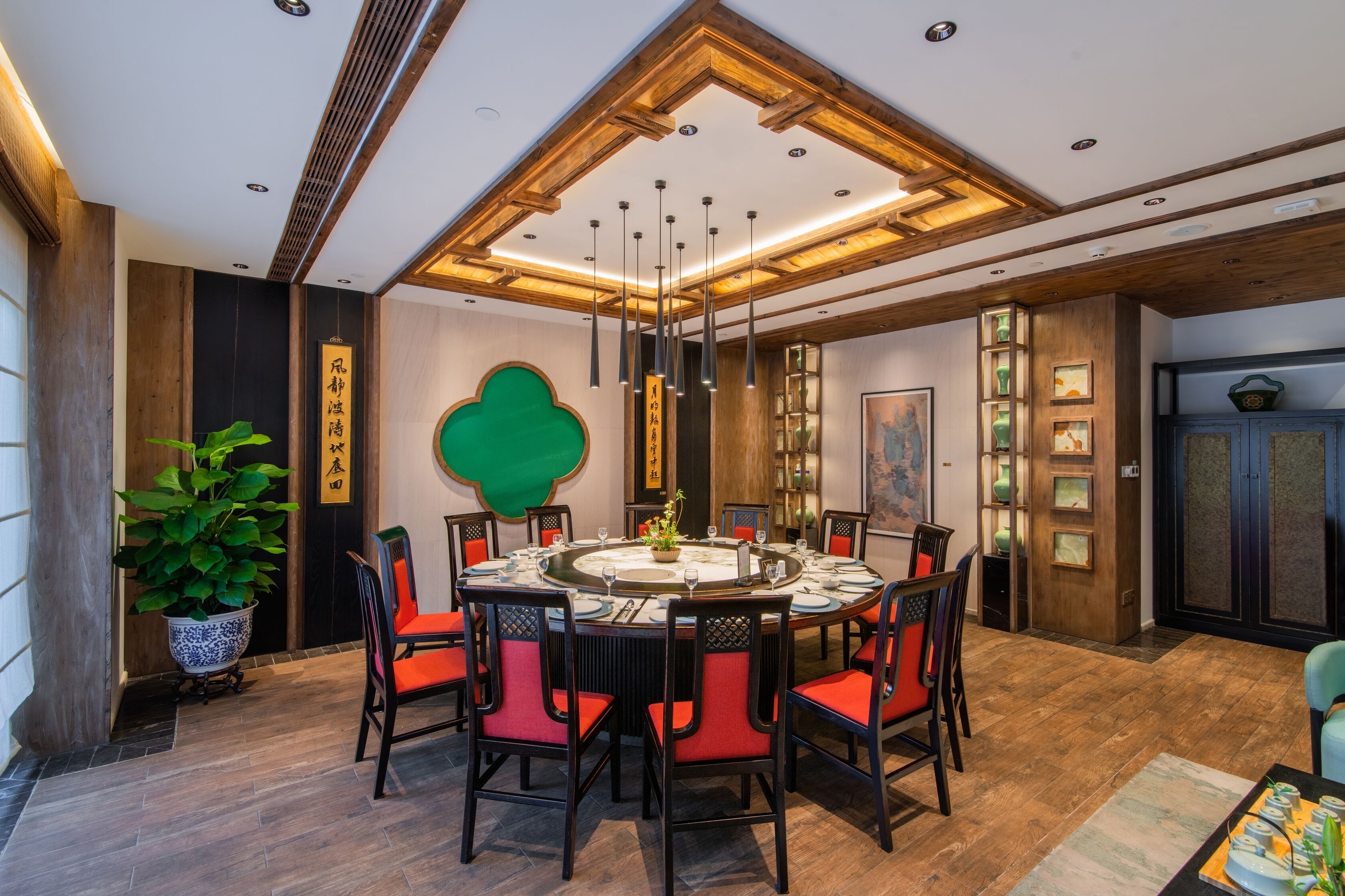 A dining area with a round table, red chairs, and a central vase.
