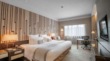 Una habitació d'hotel moderna amb un llit gran, taules de nit, un escriptori i una televisió.