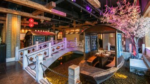 A traditional-style interior with a wooden bridge, a boat, and a cherry blossom tree. - Grand Pacific Hotel Ningbo (Ningbo)