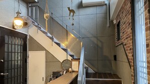 A modern interior with a wooden reception desk, a staircase, and a hanging decorative item.