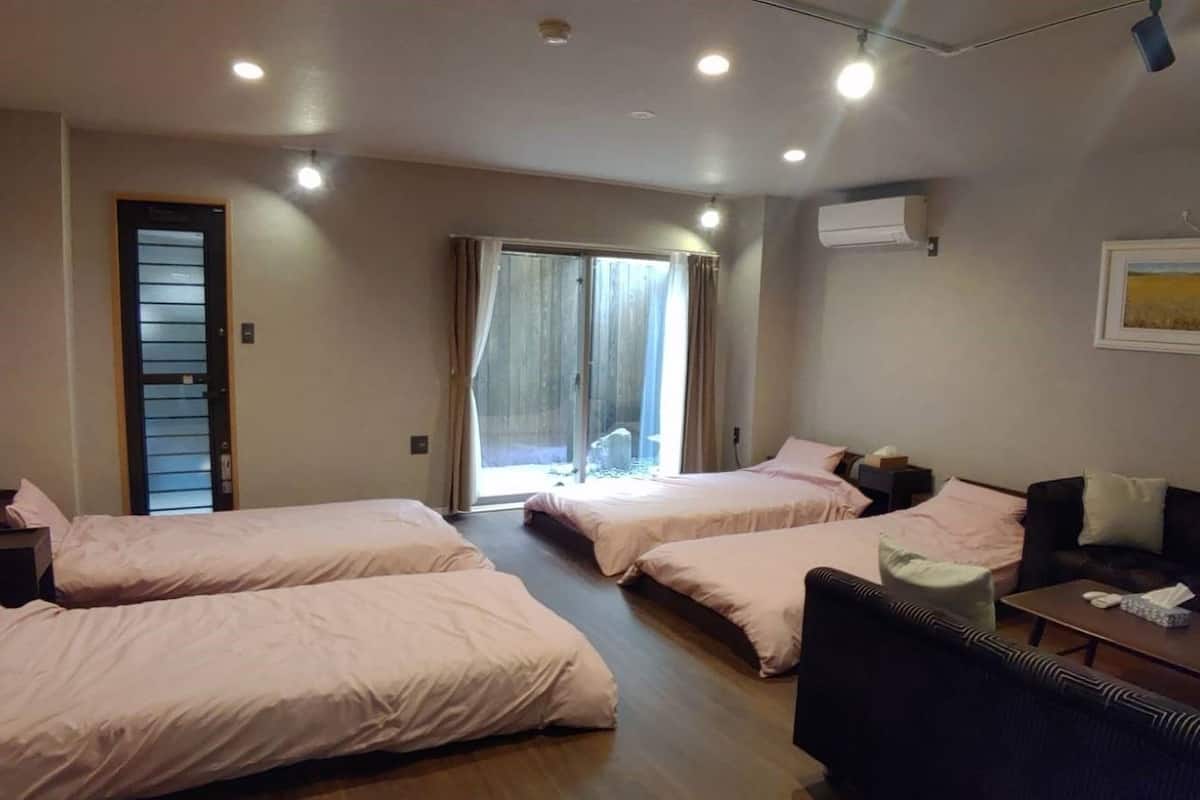 Hotelkamer met drie bedden, een bank, een salontafel en een groot raam met gordijnen.