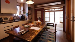 A traditional Japanese-style kitchen with a wooden dining table, a microwave, and a refrigerator.