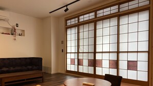 A traditional Japanese room with tatami flooring, a low table, a sofa, and a sliding shoji screen door.