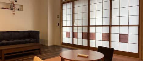 A traditional Japanese room with tatami flooring, a low table, a sofa, and a sliding shoji screen door.