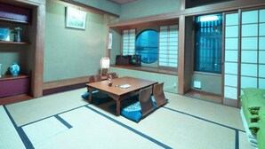 A traditional Japanese room with tatami flooring, a low table with cushions, a shoji screen, and a green futon bed.