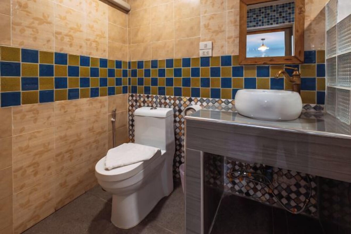 Een badkamer met toilet, wastafel en betegelde wanden.