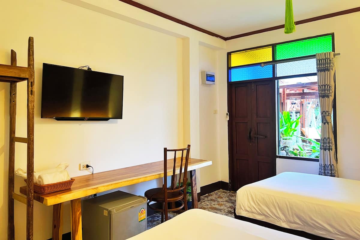 Een hotelkamer met een bed, een bureau, een televisie, een kleine koelkast en een raam met gordijnen.