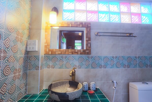 Casa de banho com azulejos estampados, lavatório suspenso, espelho, porta-toalhas e sanita.
