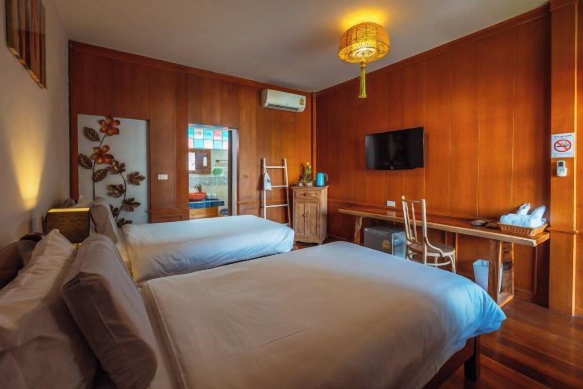 Een hotelkamer met twee bedden, een bureau, een televisie en houten lambrisering.