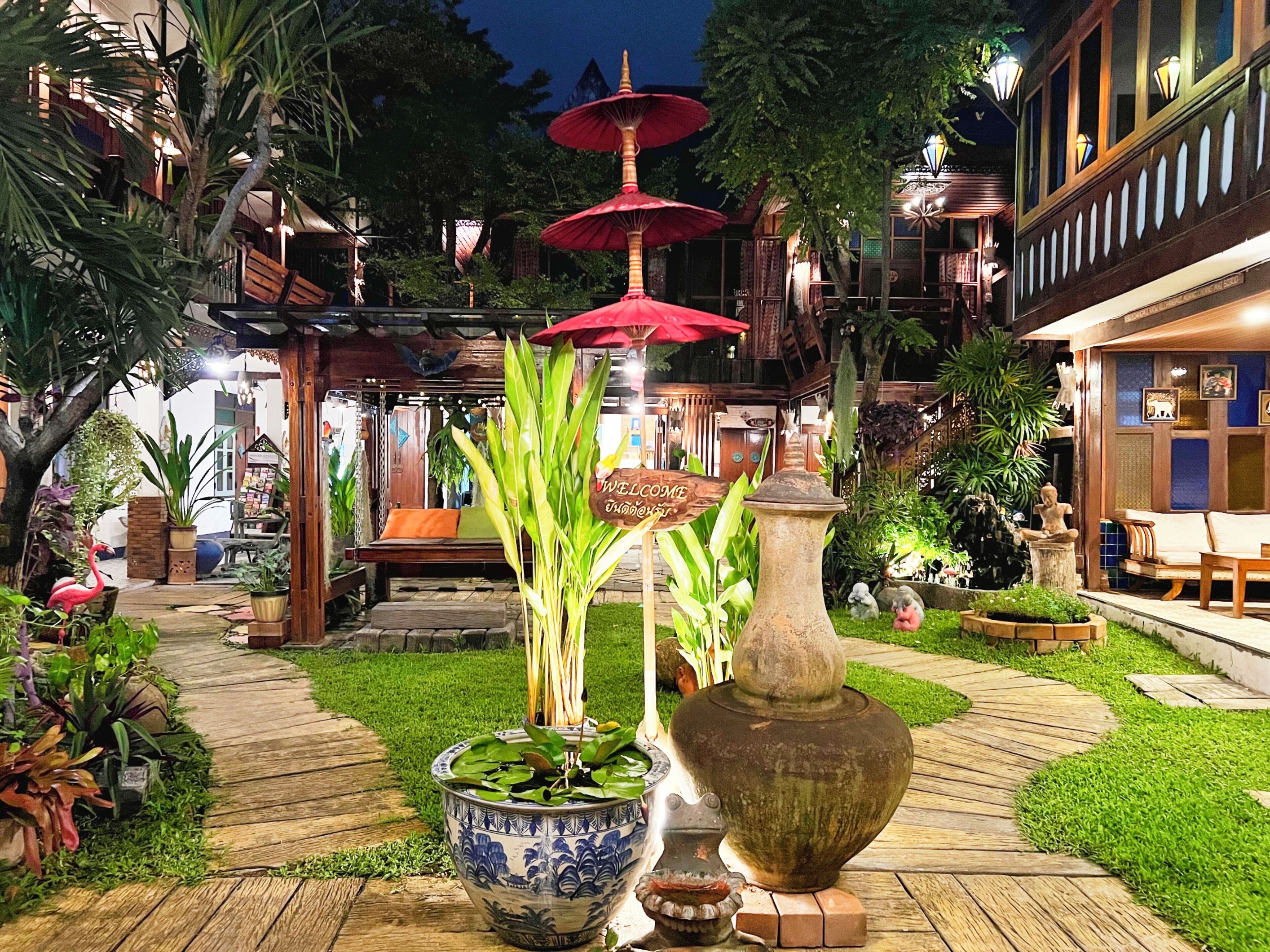 A well-lit outdoor area with a wooden bench, a large decorative vase, and a sign that reads "WELCOME".