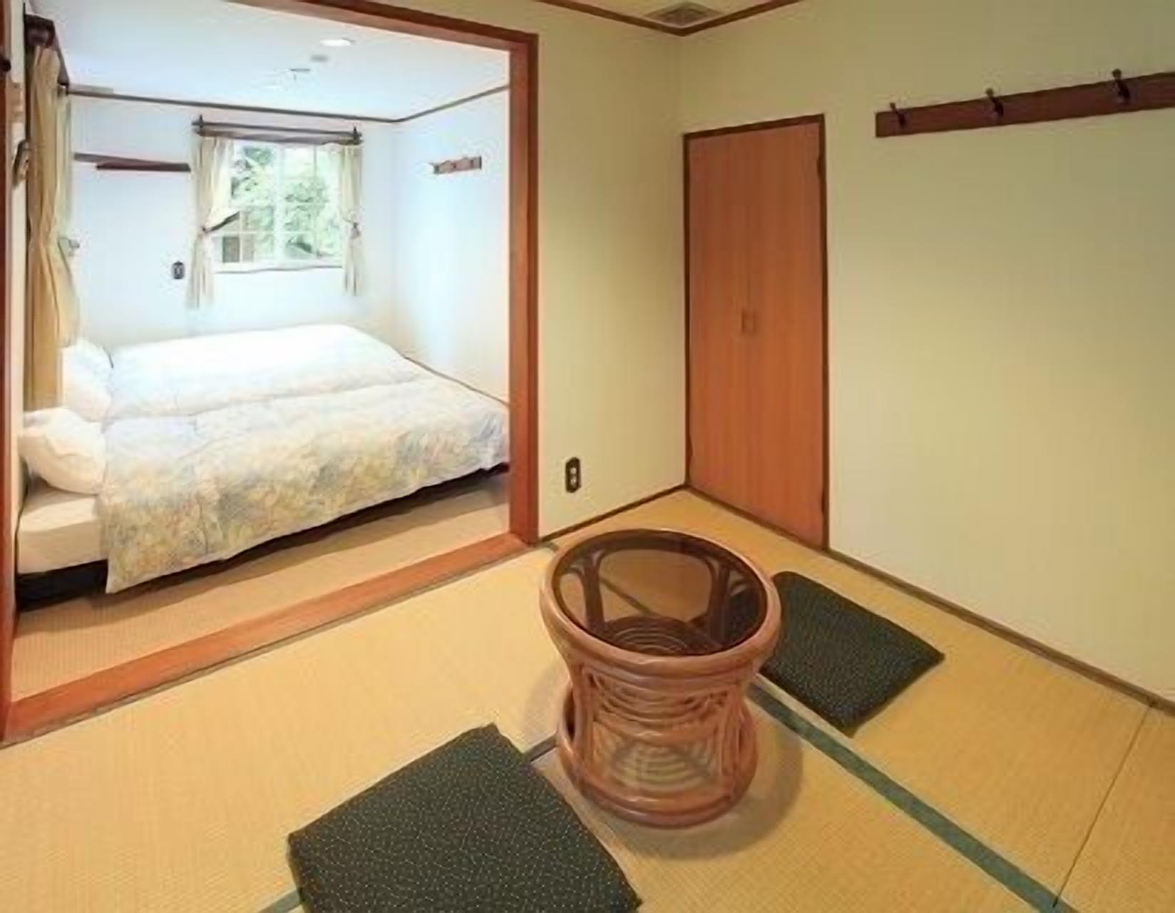 Una habitación japonesa tradicional con suelo de tatami, un futón, una puerta de madera y un shoji.