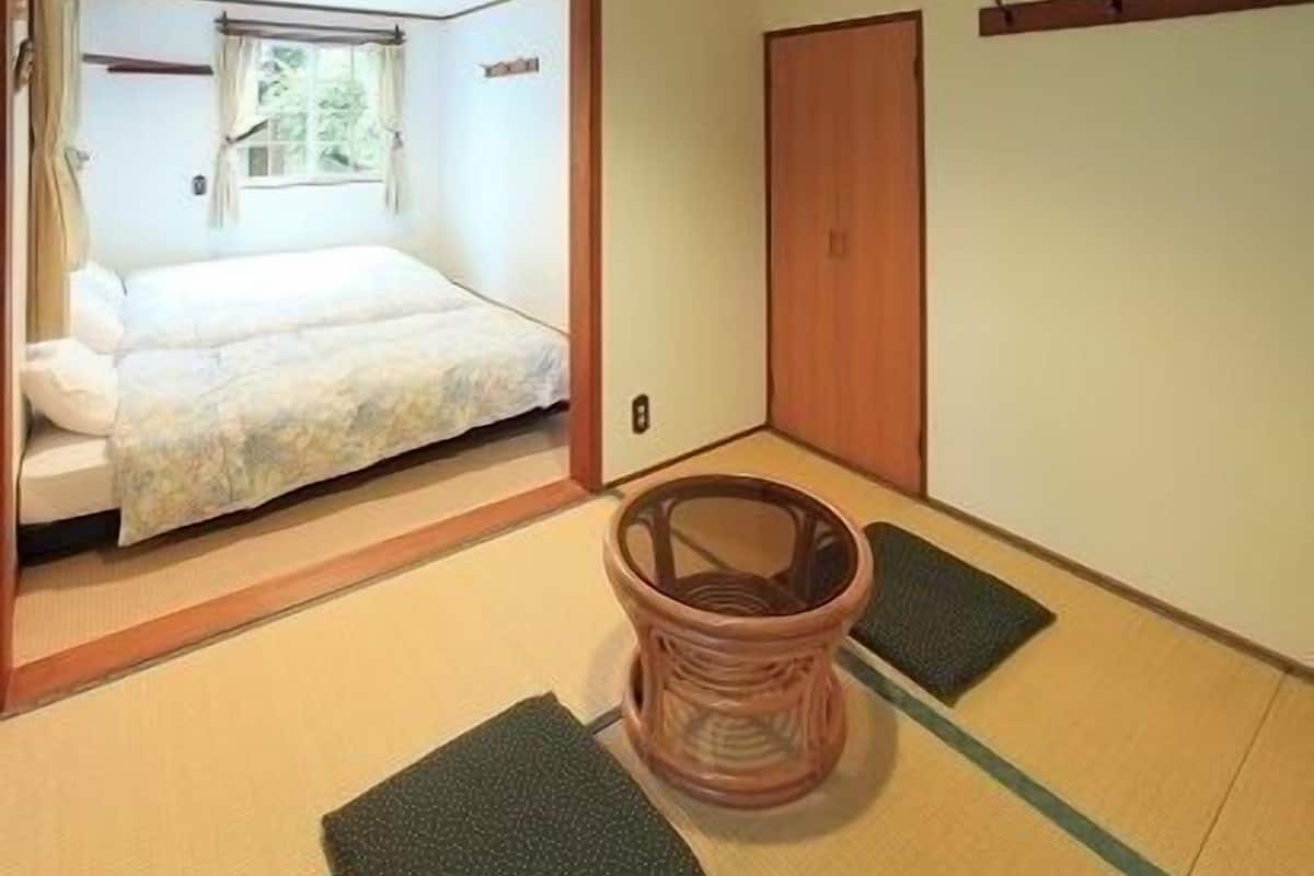 A traditional Japanese room with tatami flooring, a futon bed, a wooden door, and a shoji screen.
