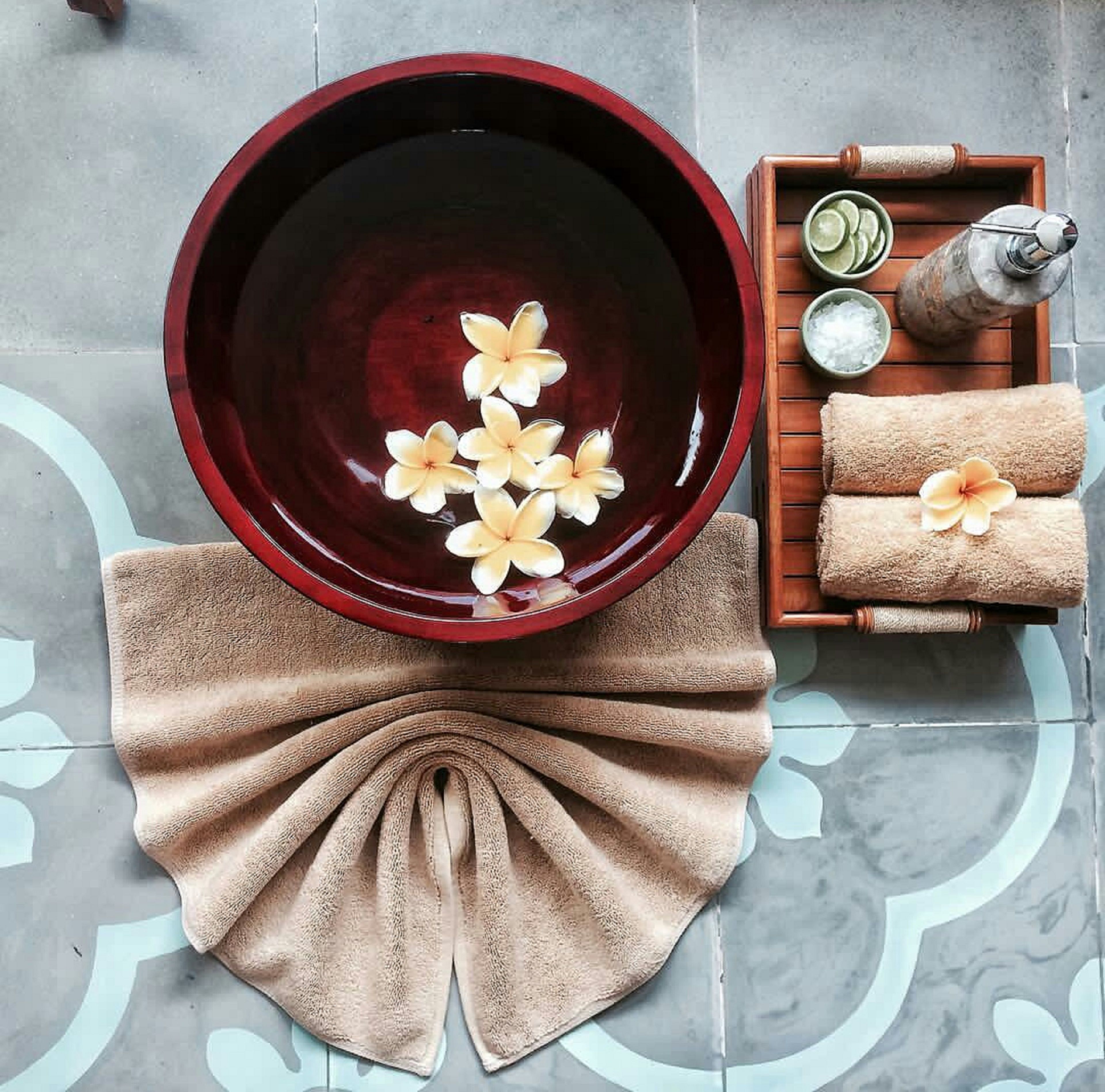 A spa setting with a large bowl containing flowers, towels, and spa products.