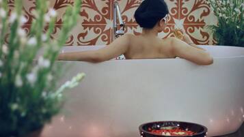 A bathtub with a decorative wall in the background.