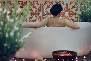 A bathtub with a decorative wall in the background.