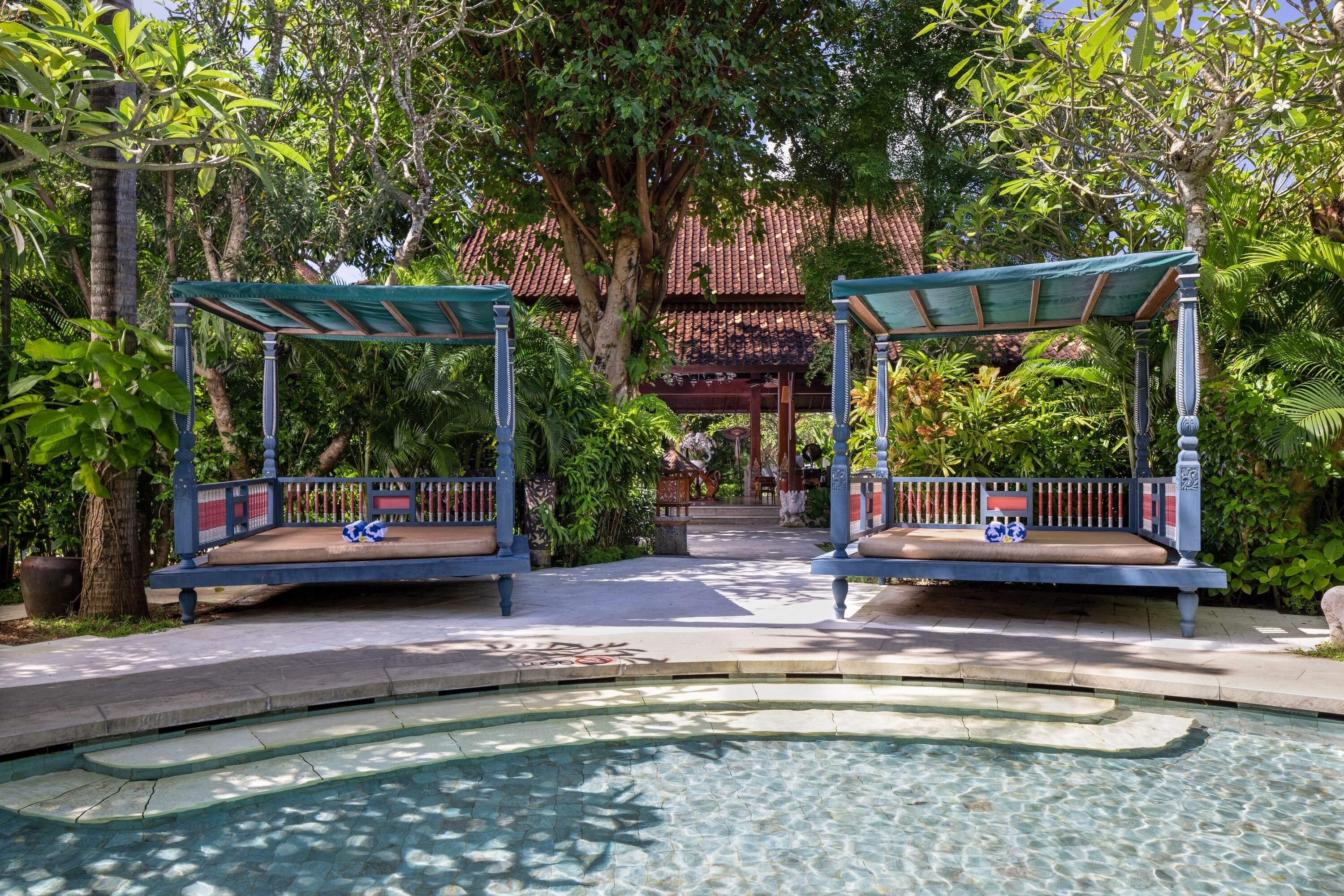 A pool area with two shaded seating areas and a clear pool.