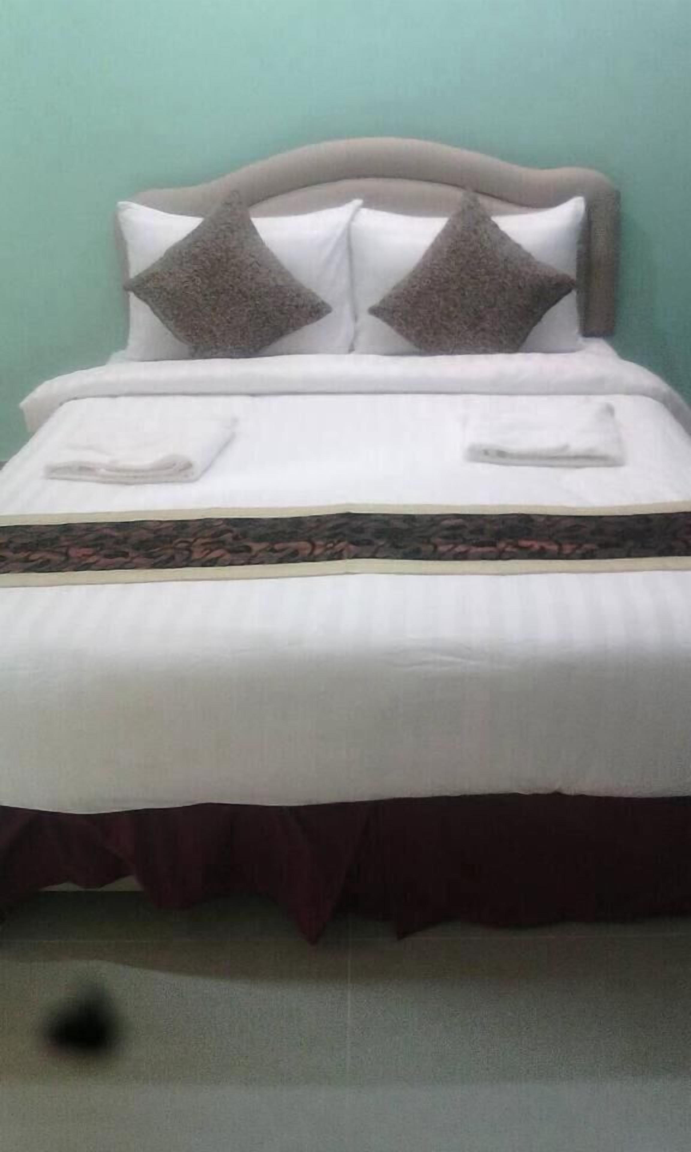Una cama con cabecera, dos almohadas y una colcha estampada.