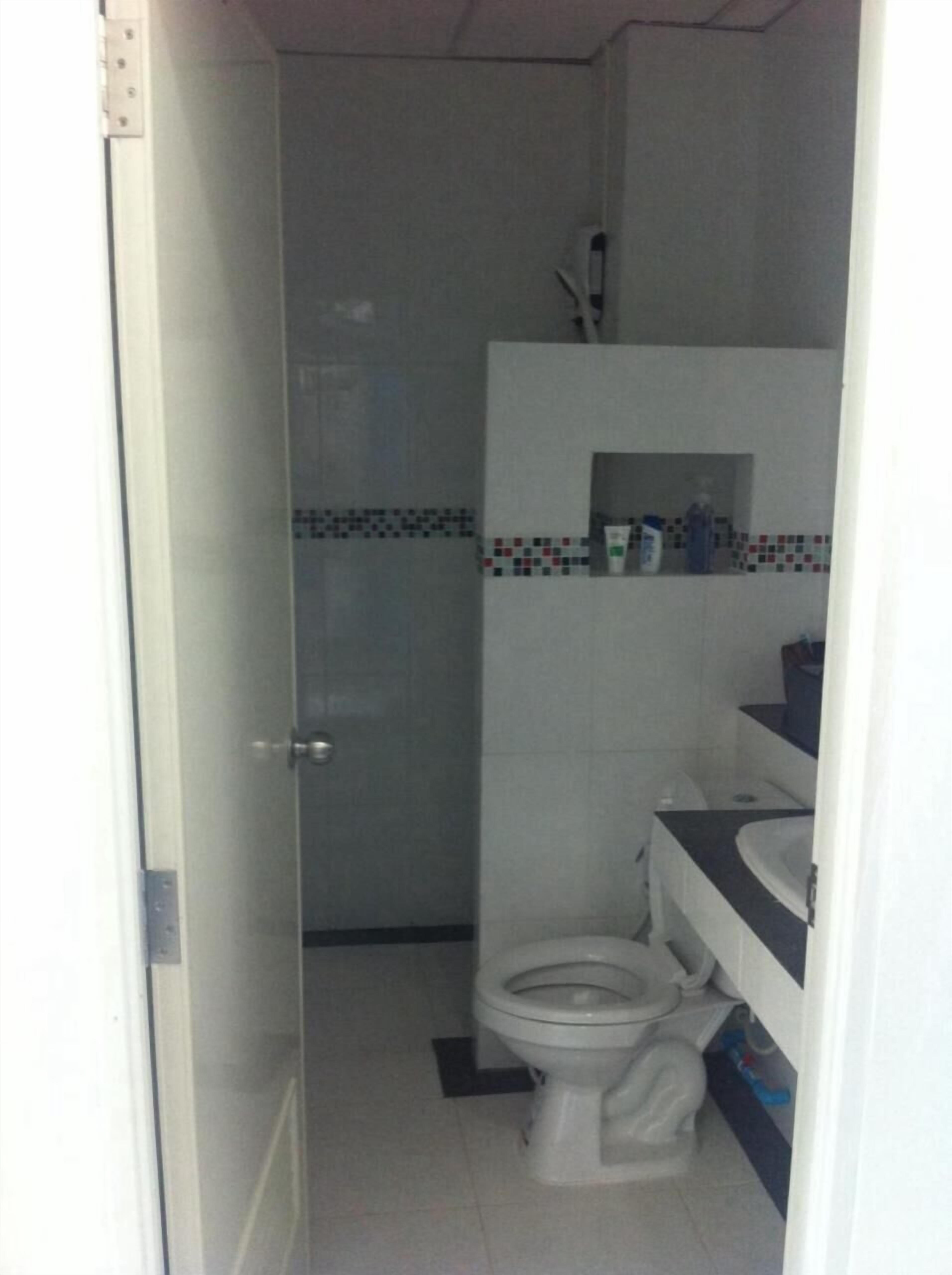 A small bathroom with a toilet, a sink, and a shower area.