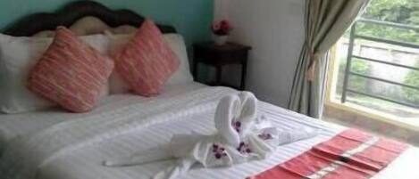 A neatly made bed with pink and white pillows, a white towel, and a red and white striped blanket.