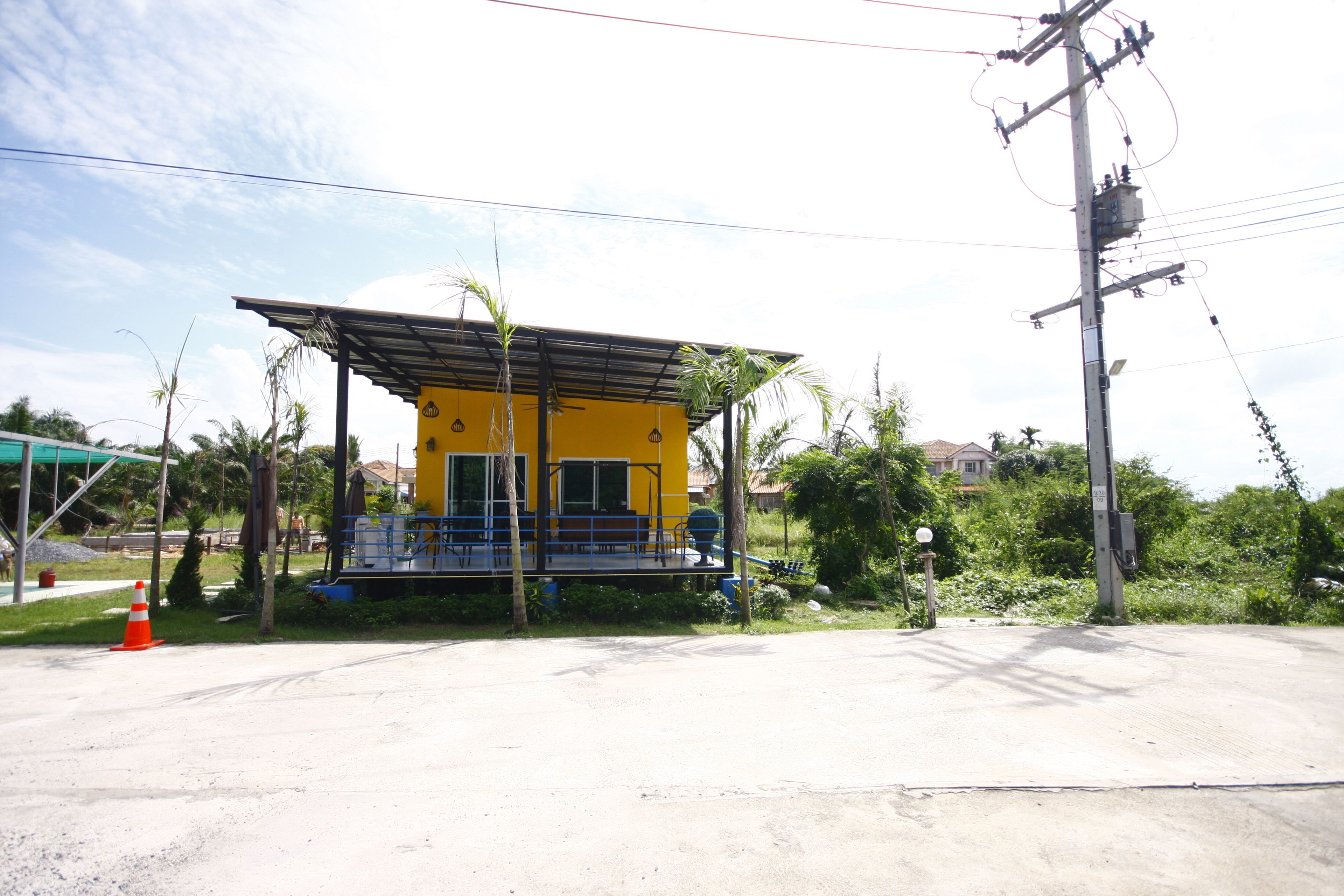 Um edifício amarelo com varanda coberta e um pequeno jardim.