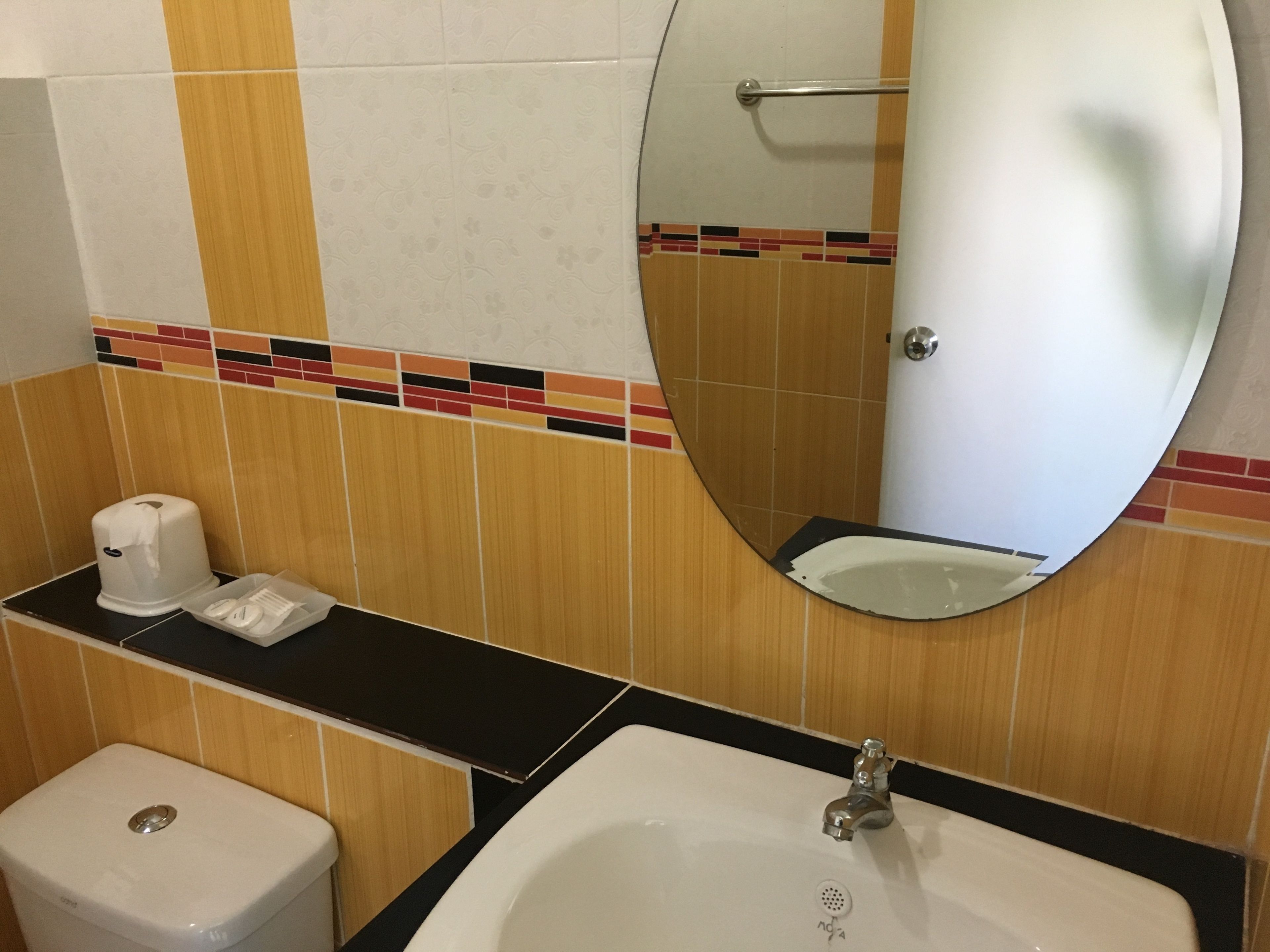 A bathroom with a toilet, sink, and mirror.