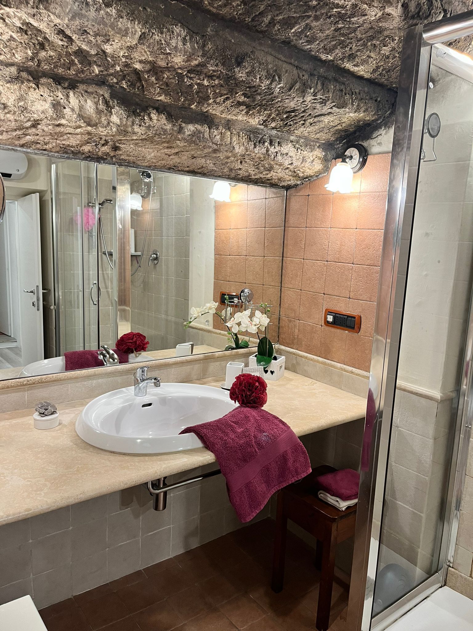 Un baño con un espejo grande, un lavamanos y una ducha.