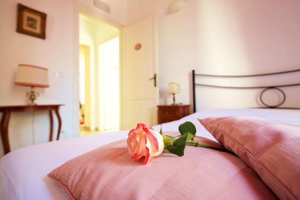 A bedroom with a bed, a bedside table, a lamp, and a door.