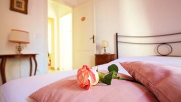 A bedroom with a bed, a bedside table, a lamp, and a door.