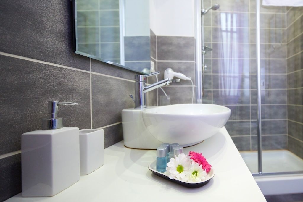 Ein modernes Badezimmer mit einem weißen Waschbecken, einem Spiegel und einer Duschkabine.