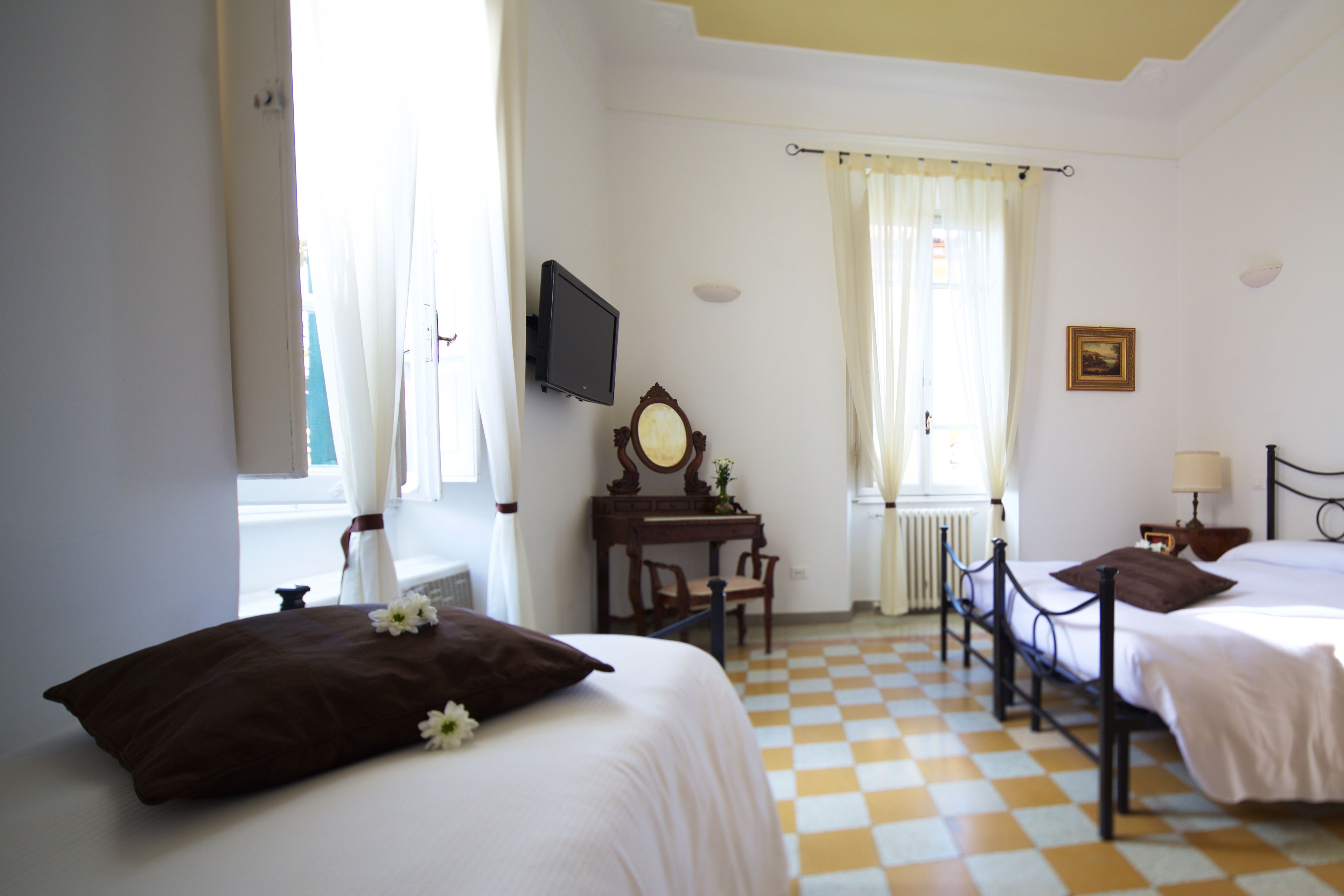 Une chambre d’hôtel avec deux lits, un bureau, une télévision et une fenêtre avec des rideaux.