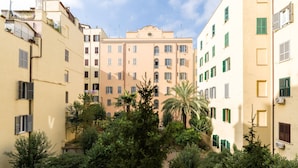 Un edifici de diversos pisos amb balcons, un pati central amb arbres i un cel serè.