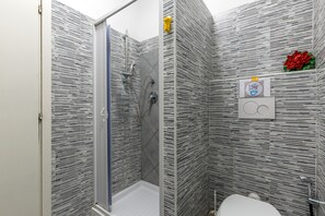 A bathroom with a shower, toilet, and a wall-mounted hand dryer. - Do Domus (Rome)