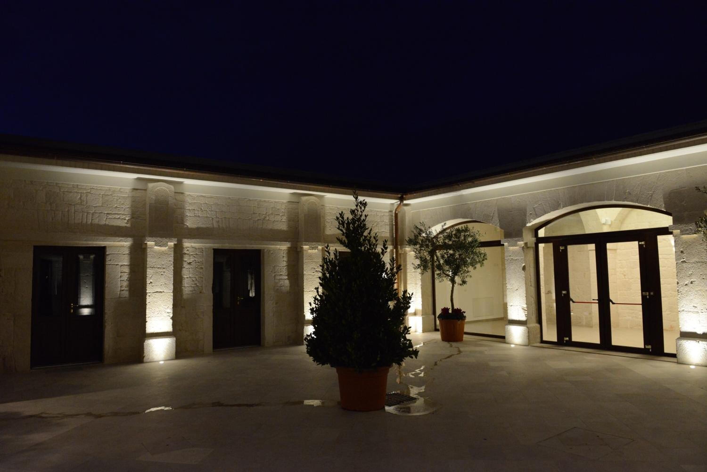 A courtyard with a stone wall, a Christmas tree, and potted plants.